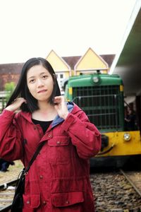 Portrait of smiling woman standing against train