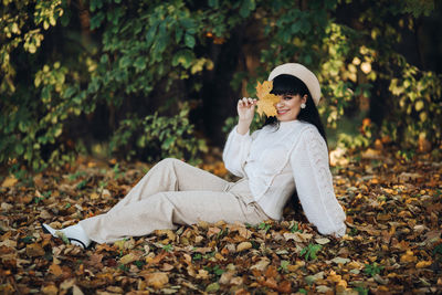 Young woman sitting on autumn leaves