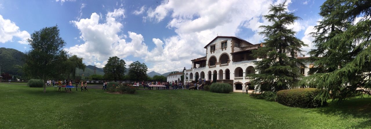 tree, architecture, grass, sky, built structure, building exterior, cloud - sky, cloud, green color, large group of people, lawn, travel destinations, travel, tourism, sunlight, person, day, tourist, park - man made space