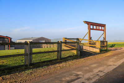 Built structure on field by road against sky