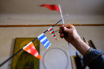 Cropped hand of man coloring bunting flags at workshop
