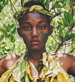 Close-up portrait of female model wearing leaves by plants