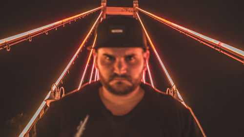 Portrait of man against illuminated bridge at night