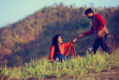 Man holding hand of woman on hill against mountain