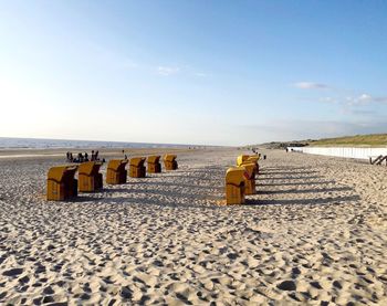 Hooded chairs on beach against sky