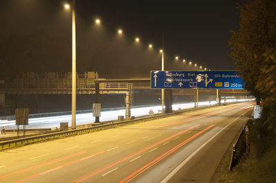 Light trails on road against sky at night