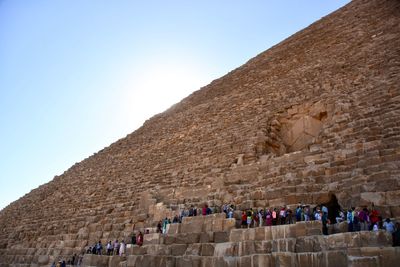 Low angle view of tourists in front of great pyramids