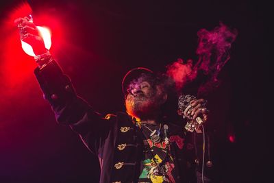 Man holding illuminated lighting equipment against black background