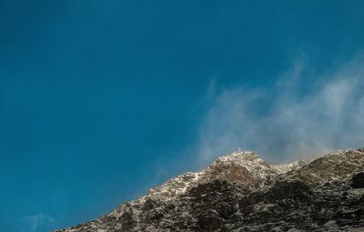 Low angle view of mountain against blue sky