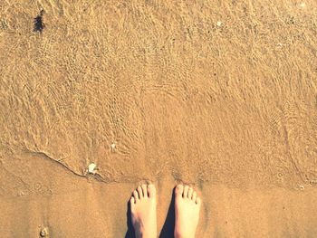 Low section of woman on sand at beach