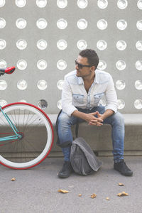 Man sitting by wall in city