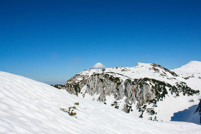 Scenic view of snowcapped mountains against clear blue sky