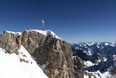 Man standing on snowcapped mountain against clear blue sky