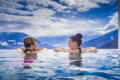 Friends in swimming pool against sky