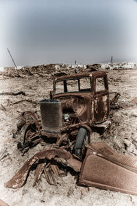 Old abandoned truck on beach against sky