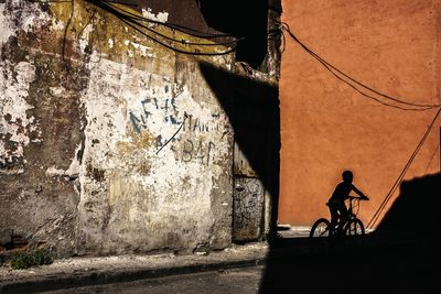 Silhouette boy with bicycle on road