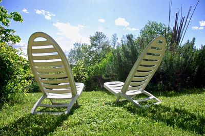View of empty chairs on field against sky