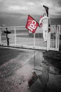 Flag on road against cloudy sky