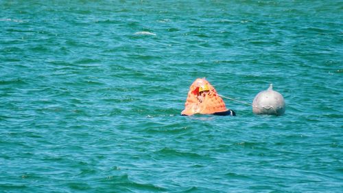 Man in lifeboat floating on turquoise sea