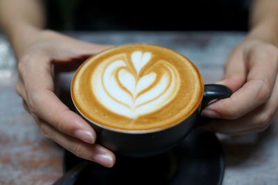 Cropped hand holding coffee cup