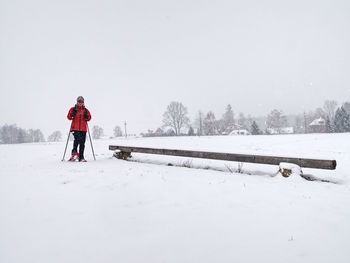 Winter snowshoing in fresh snow. woman walk in snow falling from grey clouds, windy cold weather.