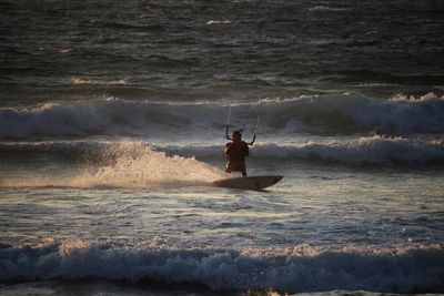 Man kiteboarding on sea during sunset