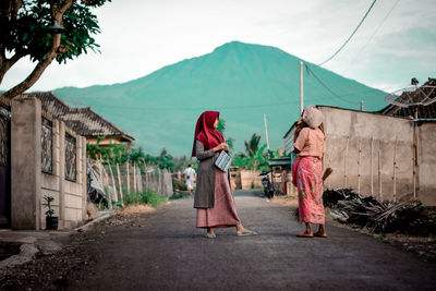 Rear view of women walking on mountain against sky