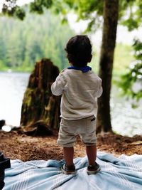 Rear view of boy standing against trees