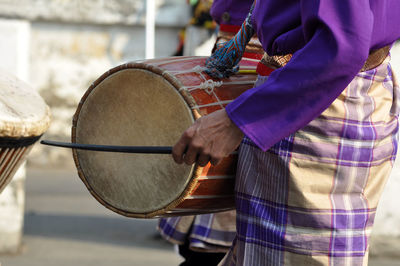 Midsection of man playing drum