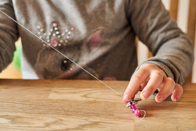 Midsection of girl making jewelry on table