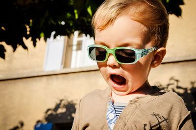 Close-up of cute boy in sunglasses with open mouth outdoors