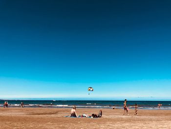 People on beach against blue sky