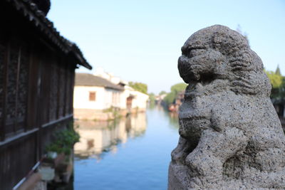 Close-up of statue against buildings and clear sky