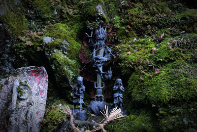 Statue amidst plants and rocks against trees