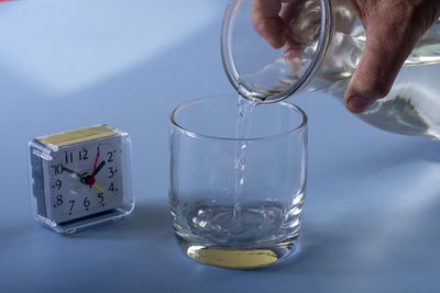 Close-up of hand holding drinking glass on table