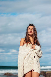 Young woman standing against sea