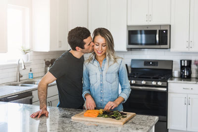 Happy friends standing by kitchen at home