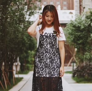 Young woman standing against trees