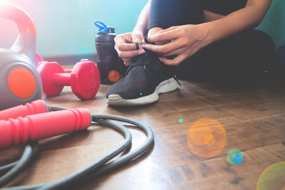 Low section of woman tying shoelace on floor