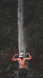 Rear view of shirtless man standing in water