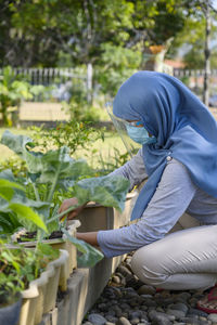 A hijab woman is wearing masker and face shield while gardening in covid 19 pandemic situation