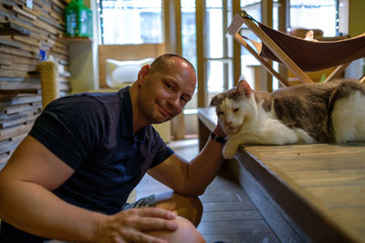 Portrait of man stroking cat while sitting at home