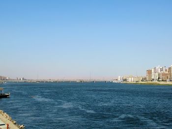 Scenic view of sea and buildings against clear sky