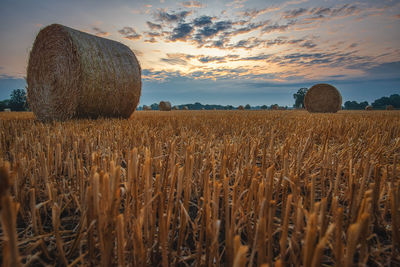 Hay bales on field against sky during sunset