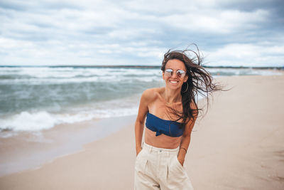 Portrait of smiling young woman standing on beach