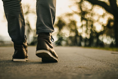 Low section of man walking on road