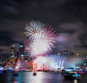 Low angle view of firework display over river at night