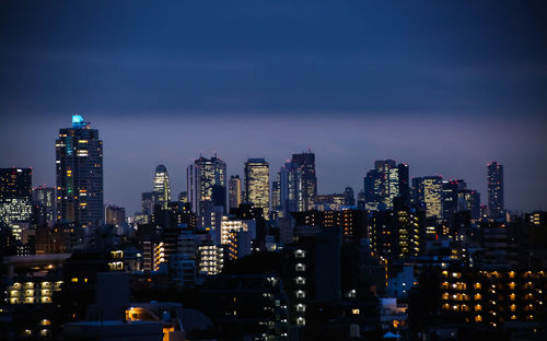 Illuminated buildings in city against sky at night