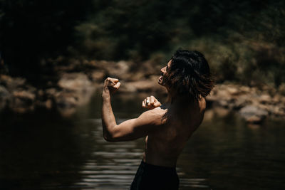 Side view of shirtless man standing in lake