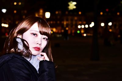 Portrait of beautiful woman in city at night